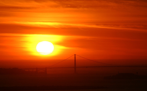 Giant sun setting over Golden Gate Bridge